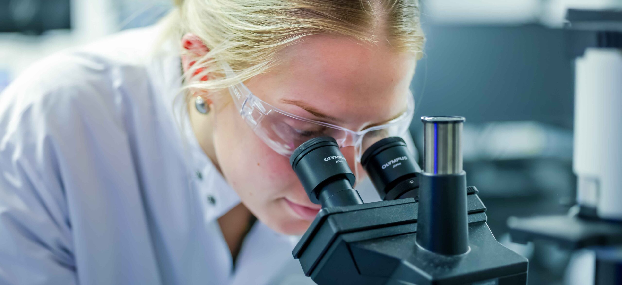 A Forge Biologics scientist looks at samples through a microscope.