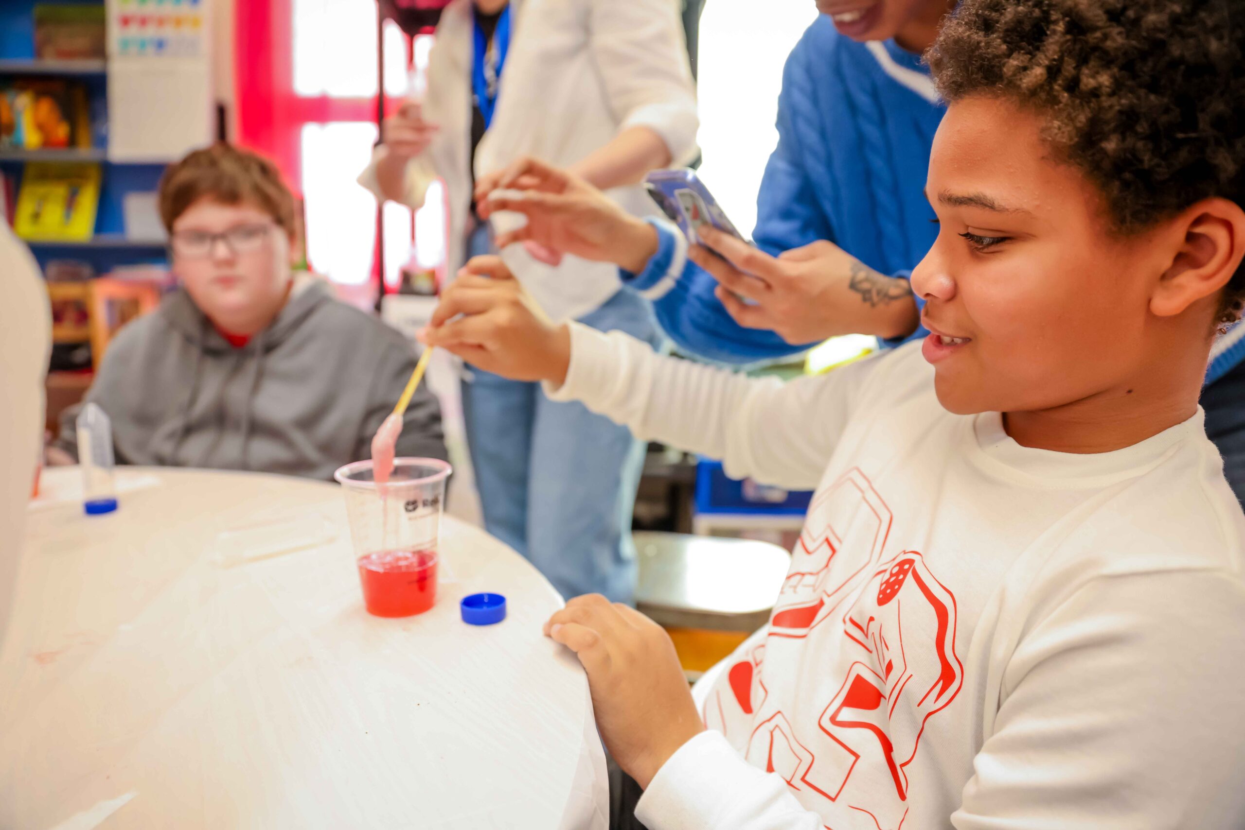 Members of the Forge team conducting an experiment to extract DNA from strawberries with children at a Columbus school.
